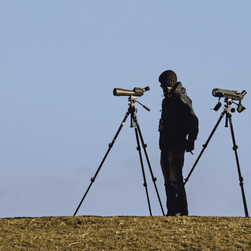 a man standing in front of a pair of binoculars