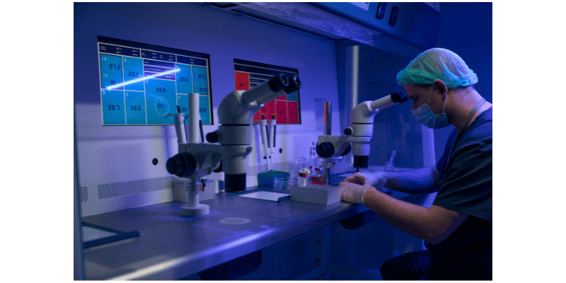 a man looking through microscopes