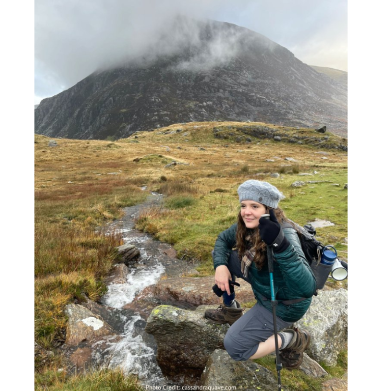 a woman kneeling on a rock in a mountain