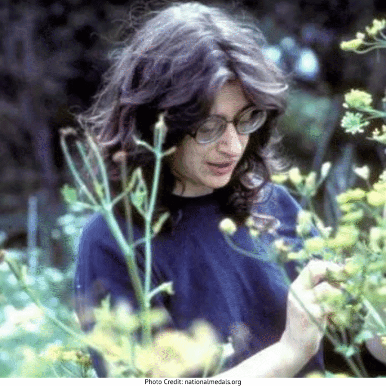 Dr. May Berenbaum in glasses looking at plants